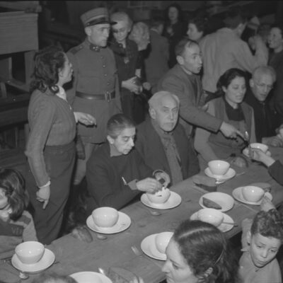 Einige der Passagiere des “Zugs in die Freiheit» während dem Essen, beaufsichtigt vom Schweizer Militär.
StadtASG_PA_Scheiwiller_Walter_25